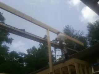 Carpenter setting a ridge beam over a new addition frame — Ice Dam Removal by Roofing Brothers in New Liberty