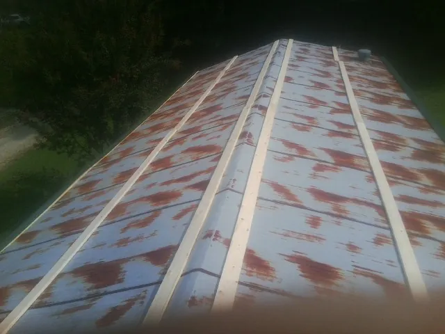 Rusted metal roof panels with new wood purlins before replacement — Storm Damage Roof Repair in New Liberty by Roofing Brothers