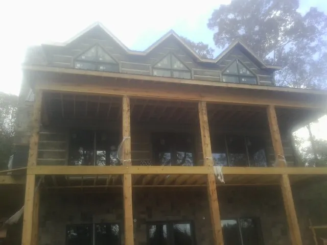 Dormers and porch framing on a large log home under construction — Roof Coating work by our crew in New Liberty