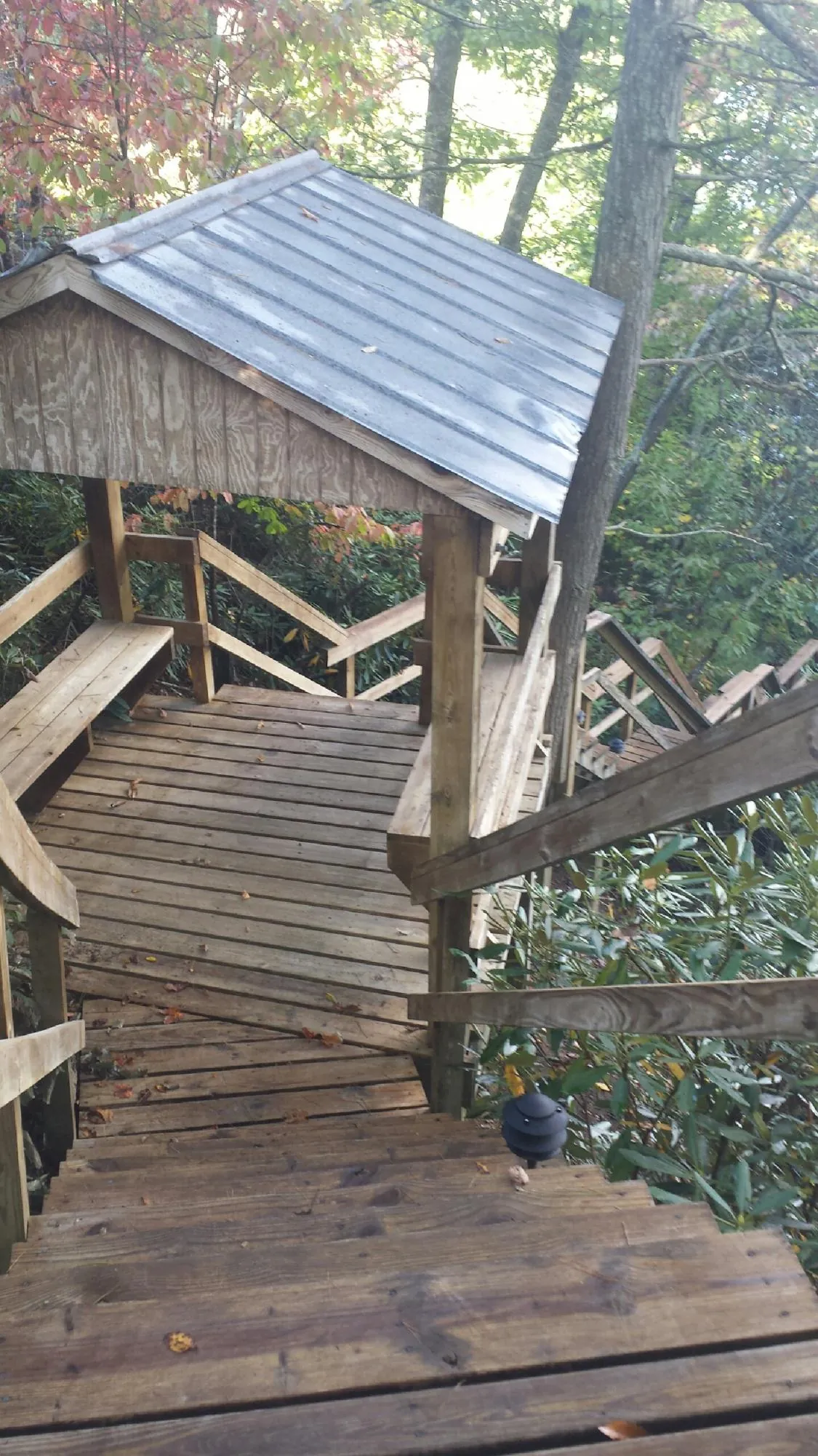 Metal roofed shelter over wooden steps on a wooded walkway — Skylight Repair & Installation work by our crew in New Liberty