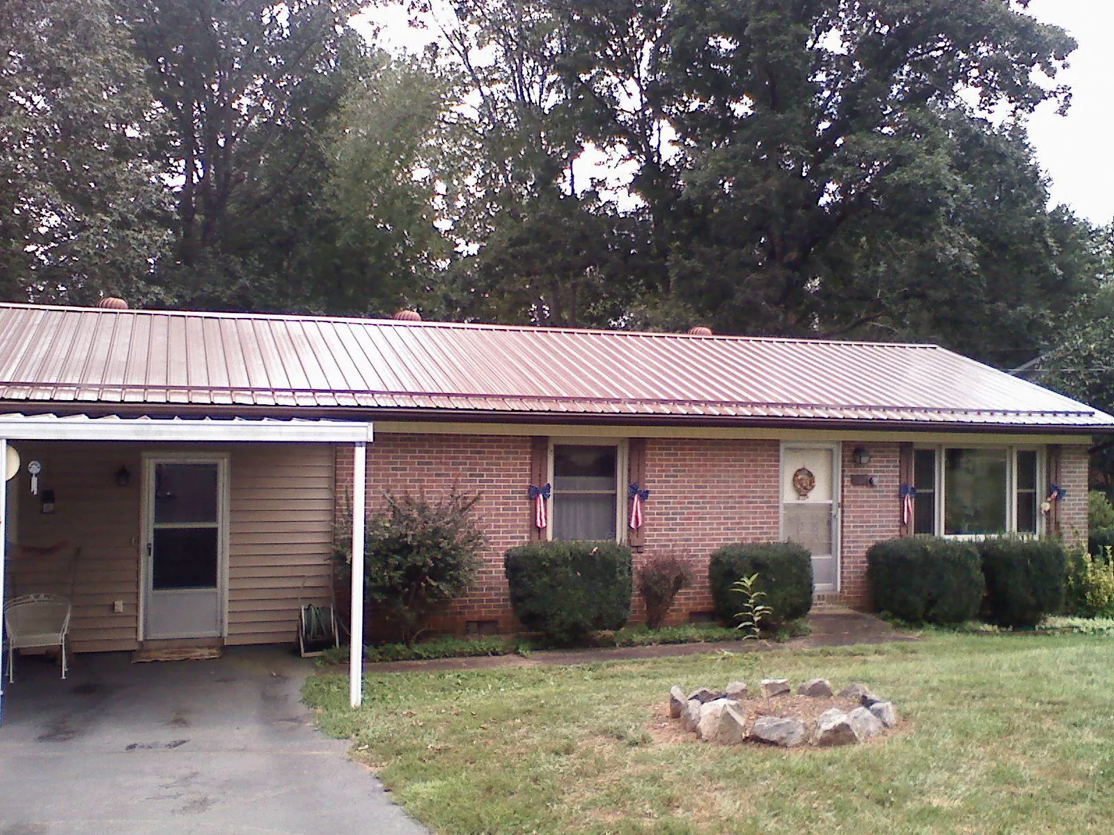 Bronze metal roof and carport on a brick ranch home — Roof Repair work by our crew in New Liberty